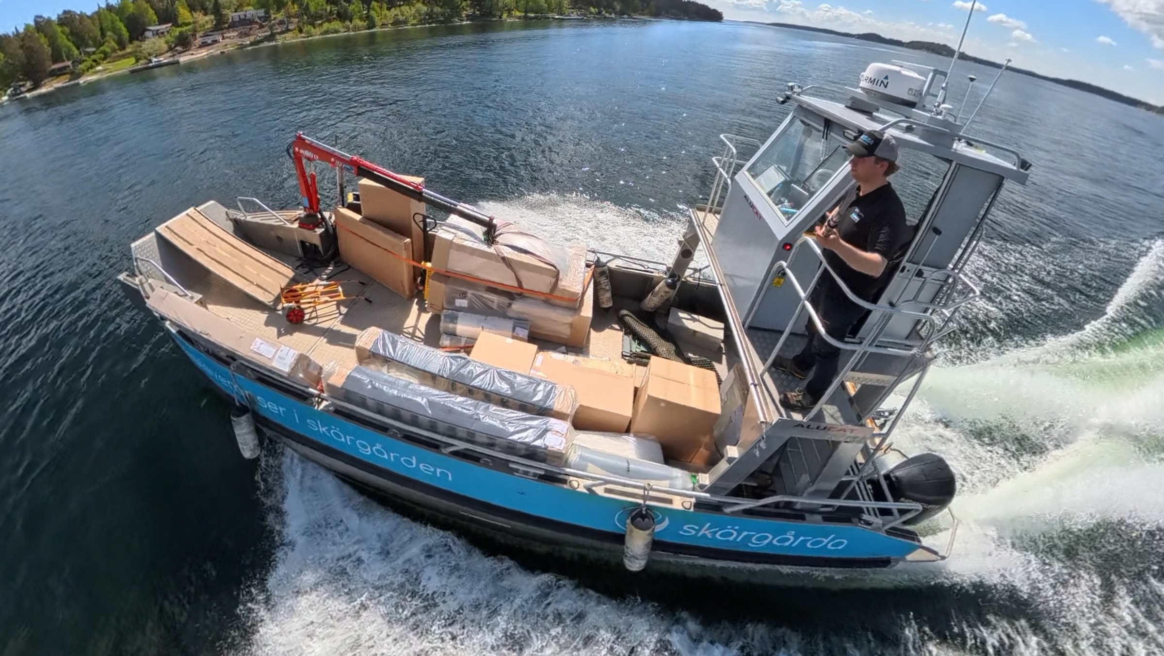 Skärgårdas båt på väg ut med däcket fullastat med paket och kranen uppfälld